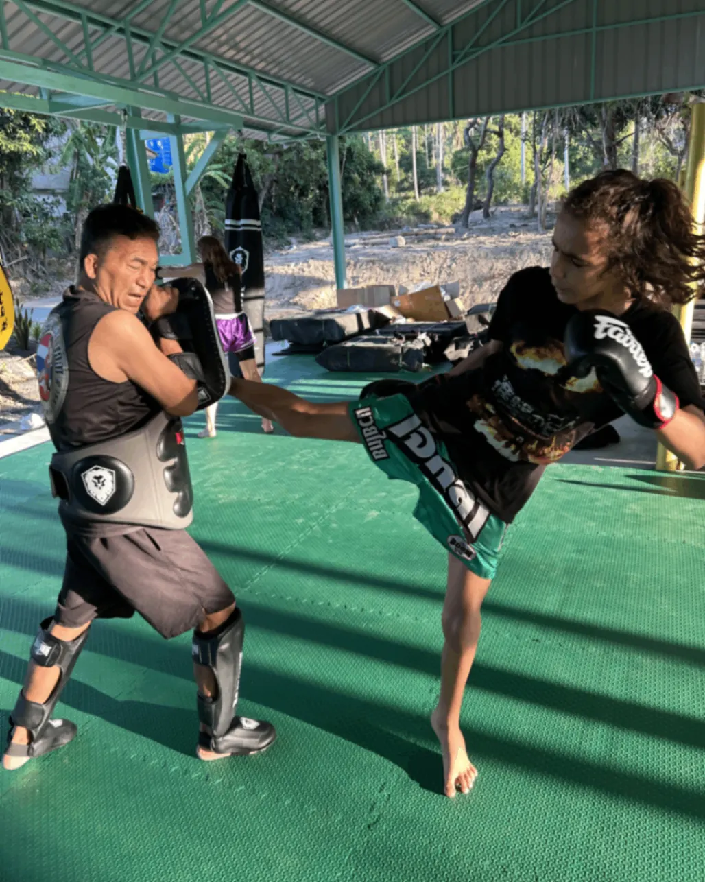 Female client landing a kick on the pads