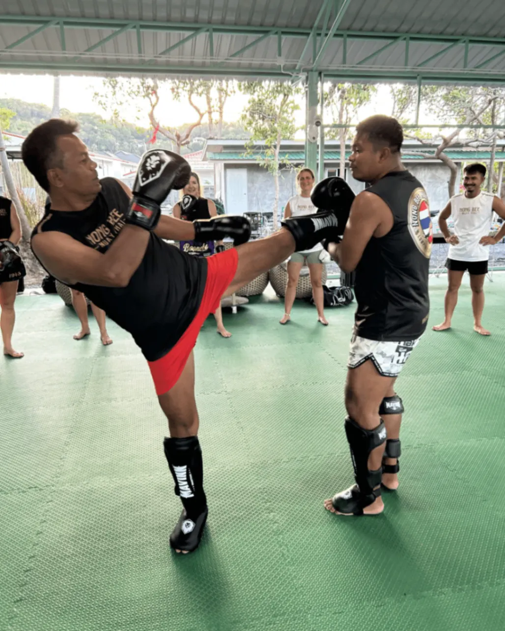 Kru Nong Bee demonstrating high kick to class