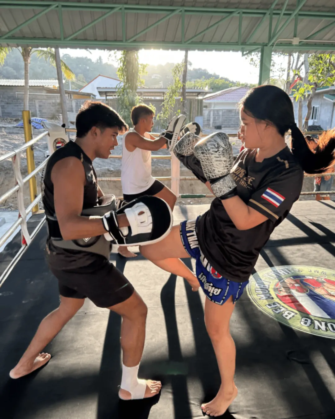Young female fighter kick training in the ring